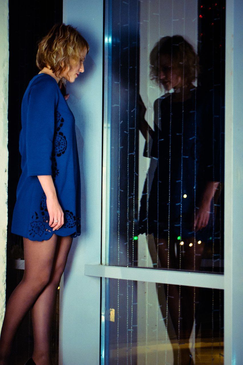 Side view of woman standing by glass window