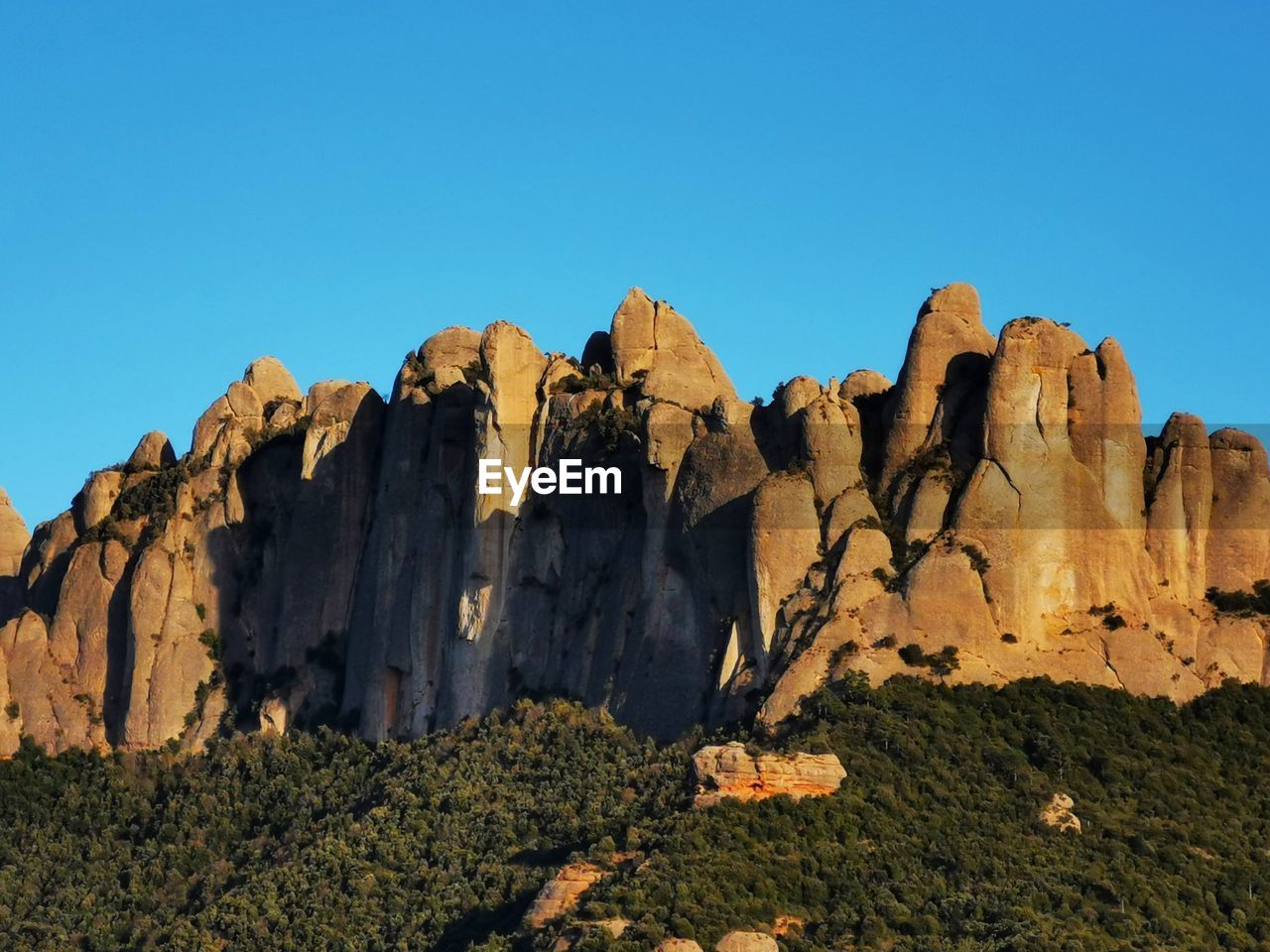 Rock formations on landscape against clear blue sky