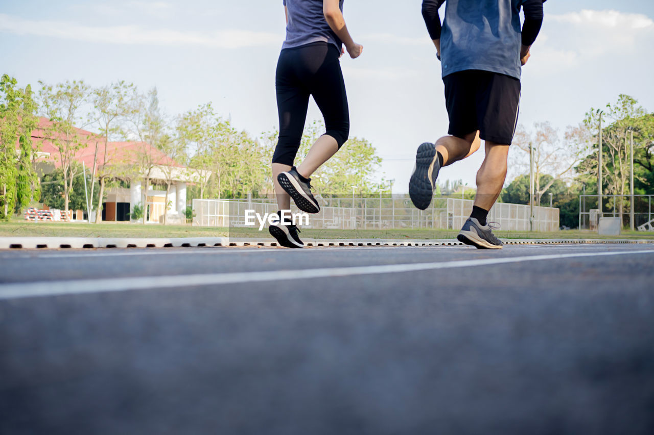 Low section of friends running on road