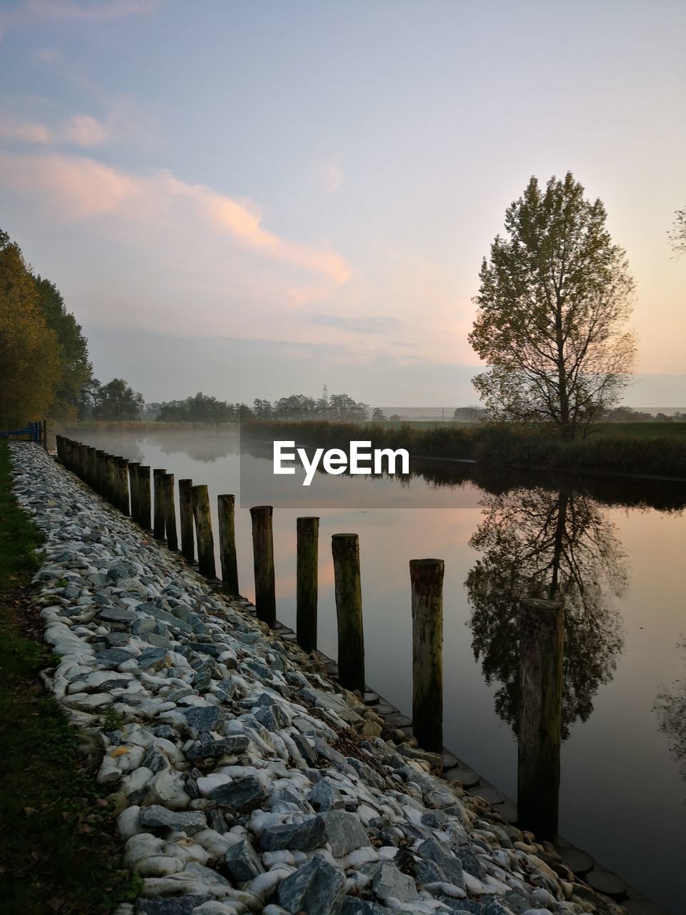 WOODEN POSTS ON LAKE AGAINST SKY