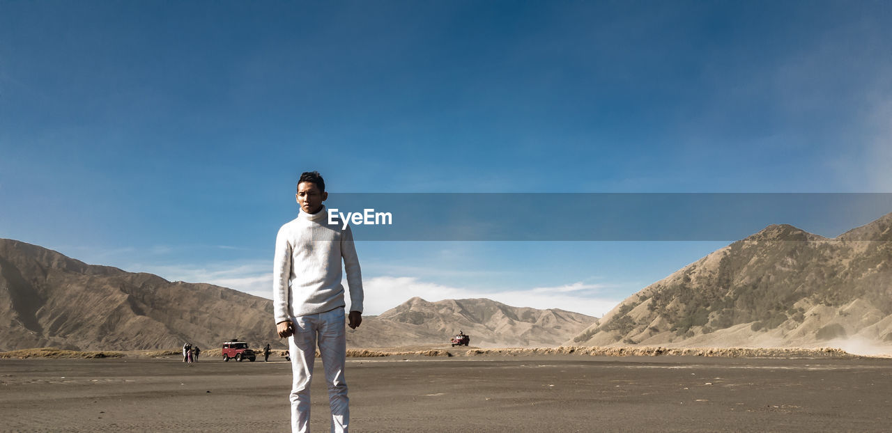 Portrait of man standing at desert against mountain 