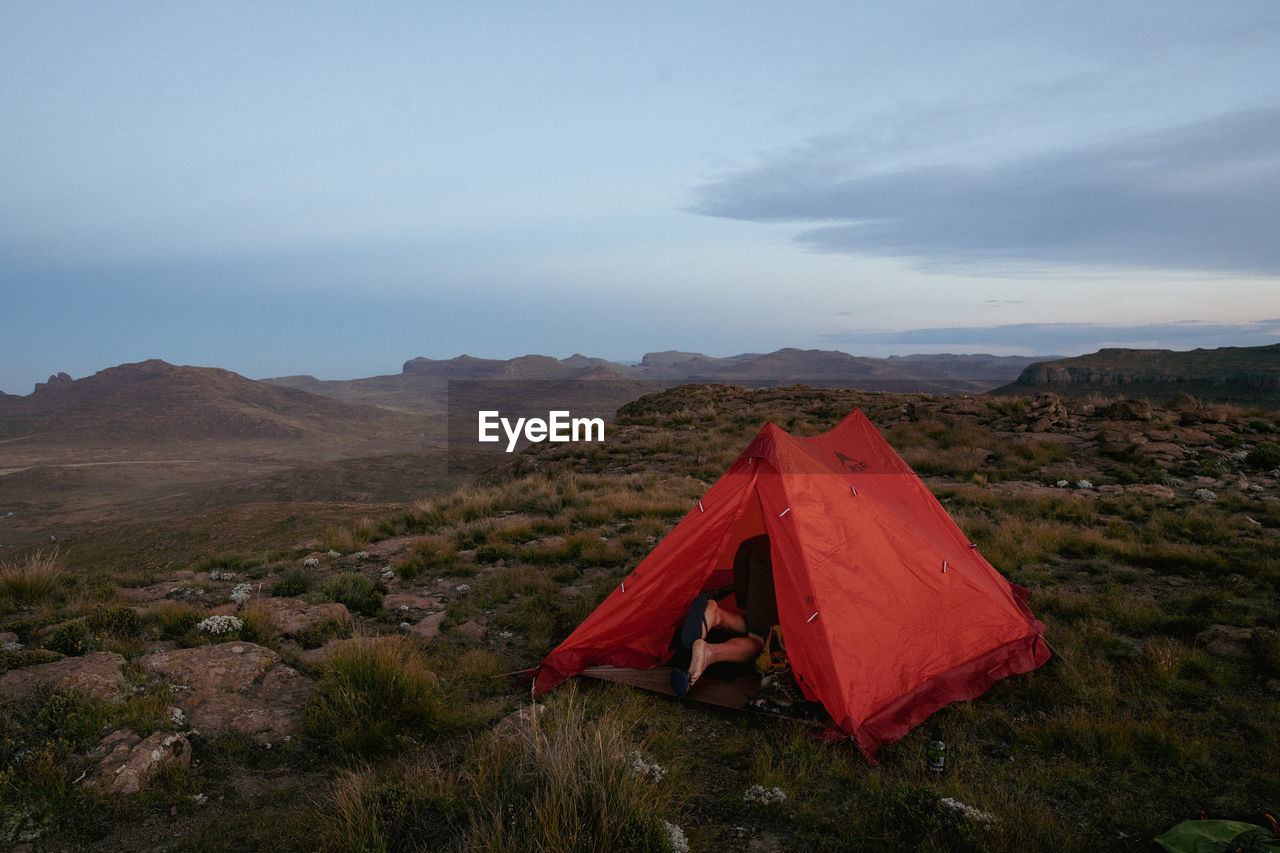 Scenic view of mountains against sky with tent, camping. 