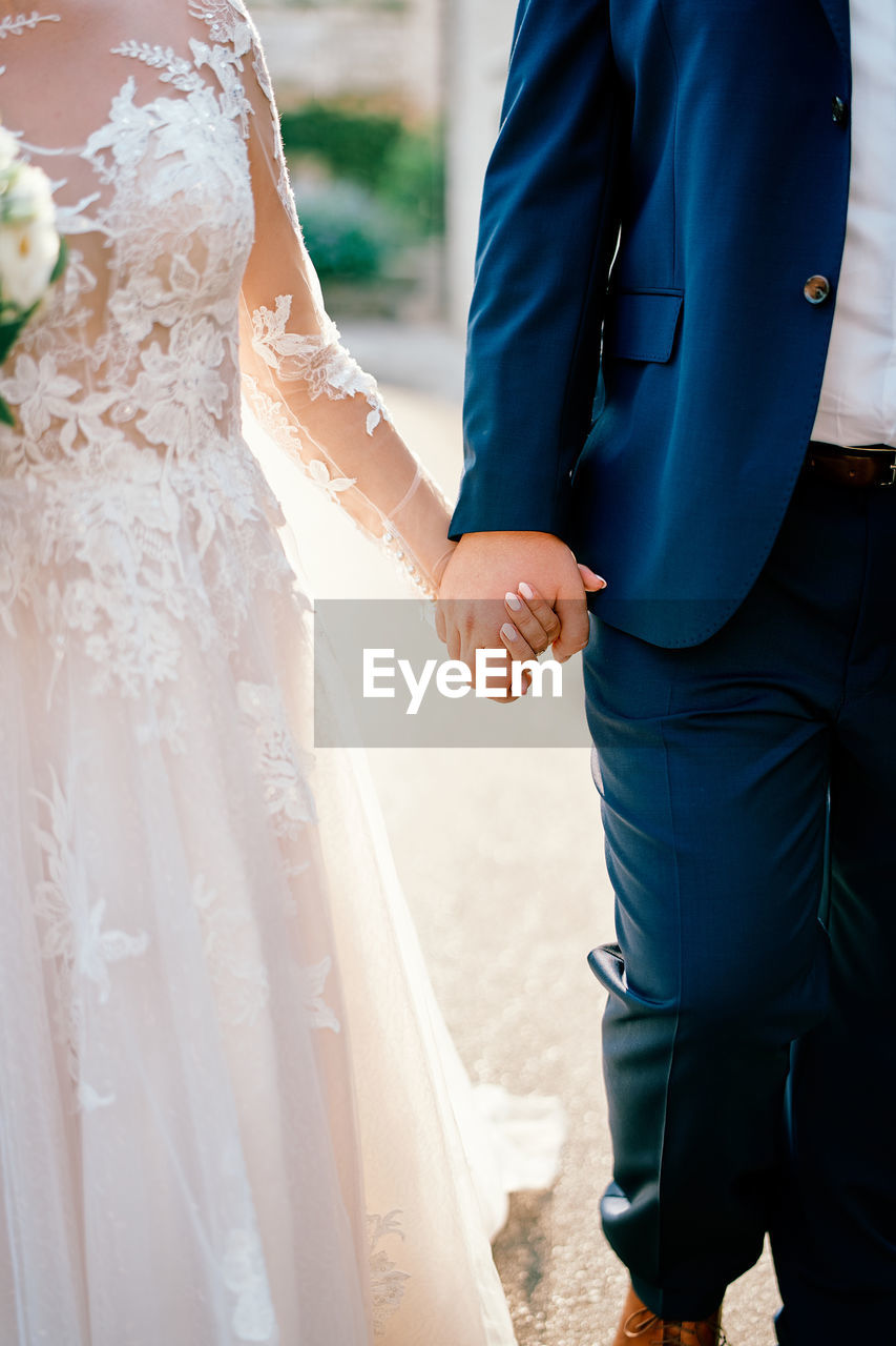 midsection of bride holding bouquet