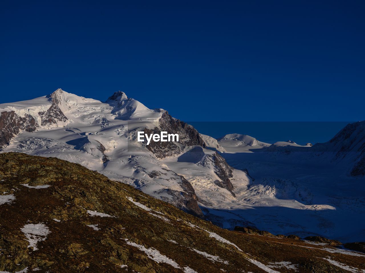 Scenic view of snowcapped mountains against clear blue sky