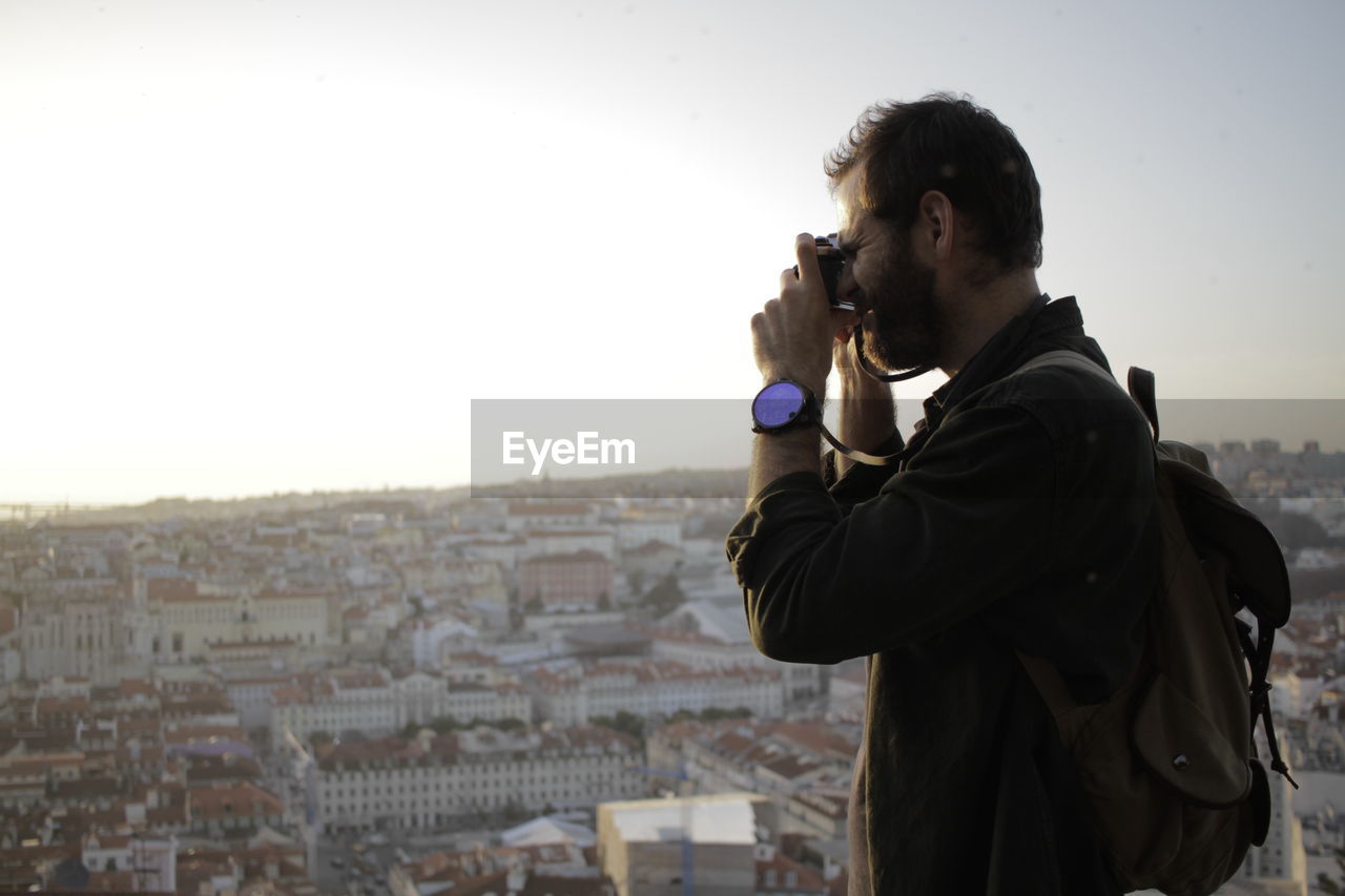 Man photographing cityscape against clear sky