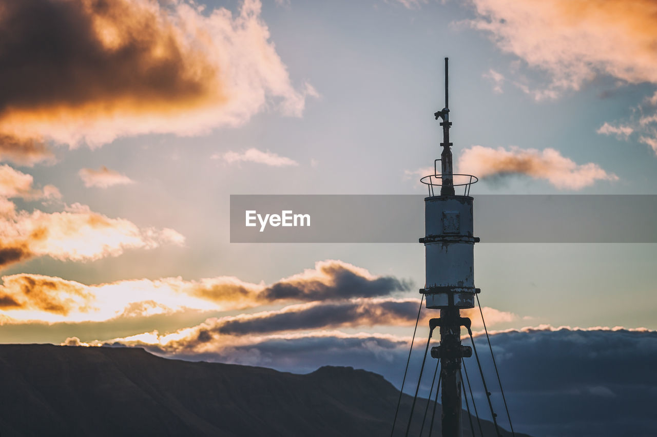 LOW ANGLE VIEW OF TOWER AGAINST SKY DURING SUNSET