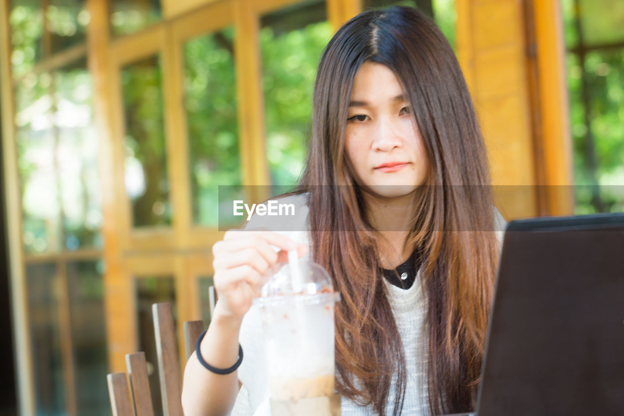 Portrait of woman with laptop having drink in cafe