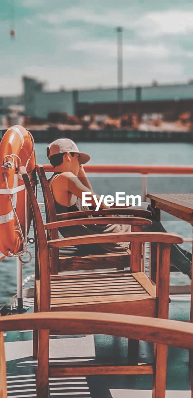 Man sitting on chair by table and sea