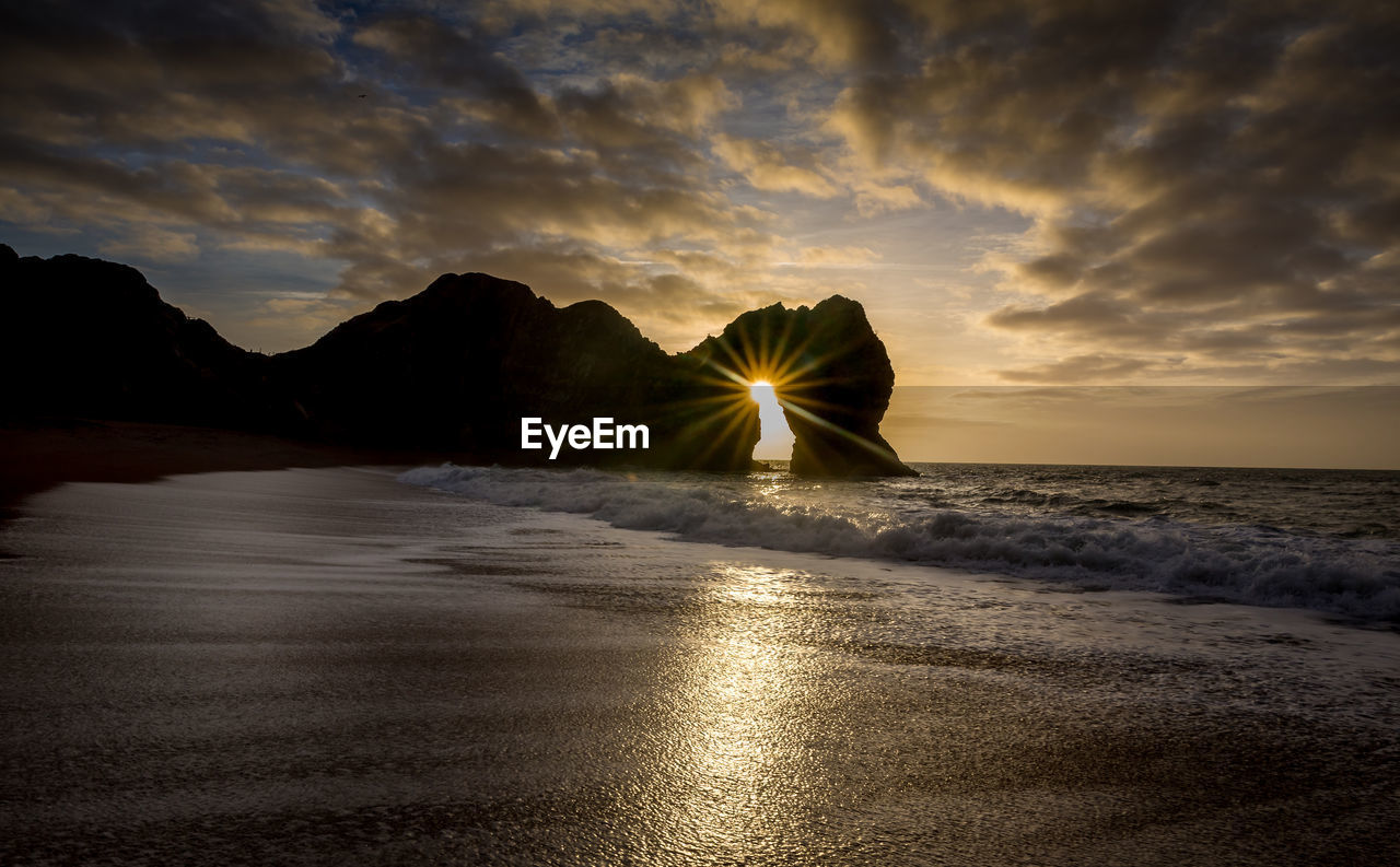 Scenic view of sea against cloudy sky during sunset