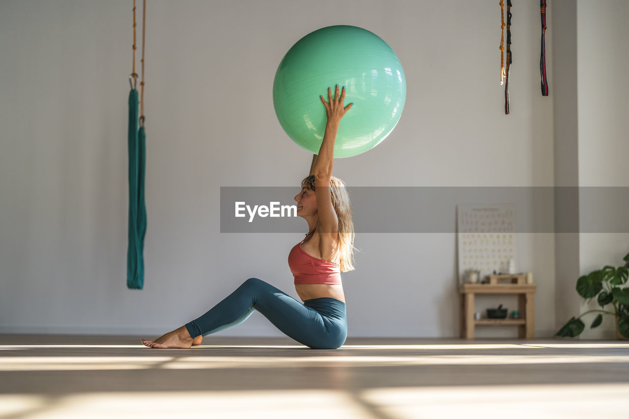 Woman exercising with fitness ball sitting in yoga studio