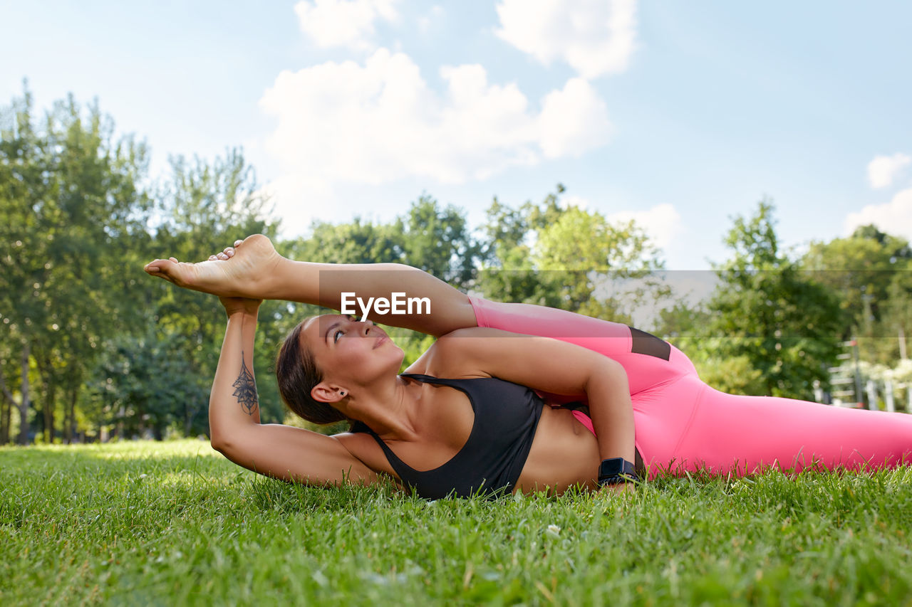 low section of woman exercising on field against sky