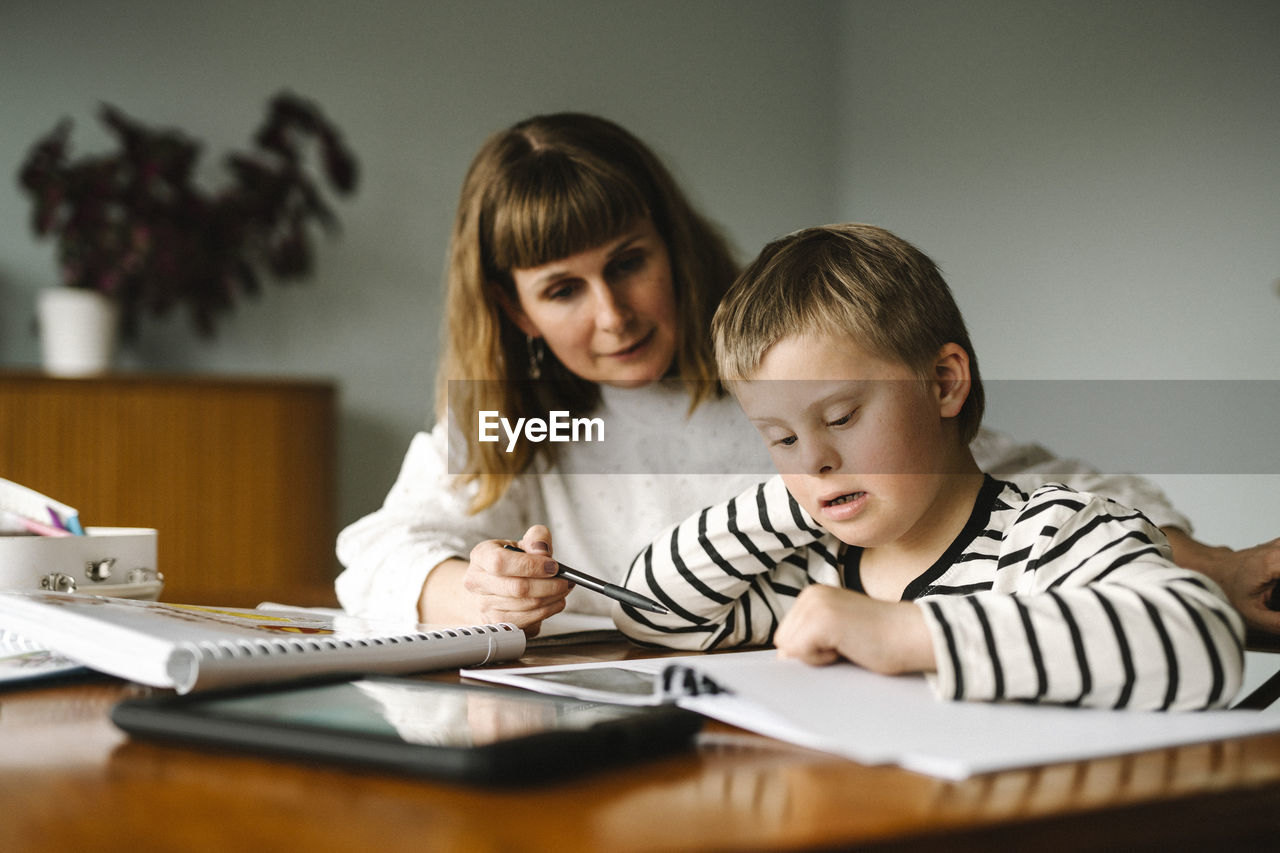 Mother teaching son with disability during homeschooling at home