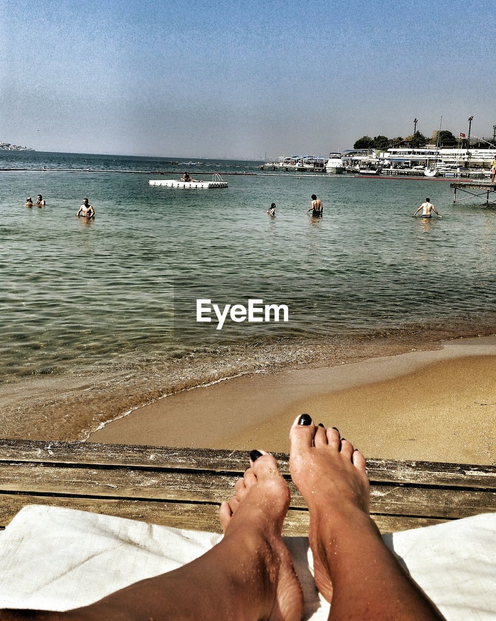 LOW SECTION OF MAN RELAXING ON BEACH AGAINST SKY