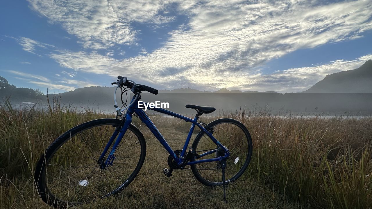 bicycle, transportation, sky, mountain bike, landscape, cycling, nature, environment, cloud, grass, mountain, vehicle, scenics - nature, sports equipment, land, mode of transportation, road bicycle, plant, beauty in nature, travel, mountain biking, field, activity, land vehicle, bicycle wheel, no people, tranquility, non-urban scene, wheel, mountain range, tranquil scene, rural scene, racing bicycle, sports, sunlight, cycle sport, outdoors, day, holiday, adventure, plain, vacation