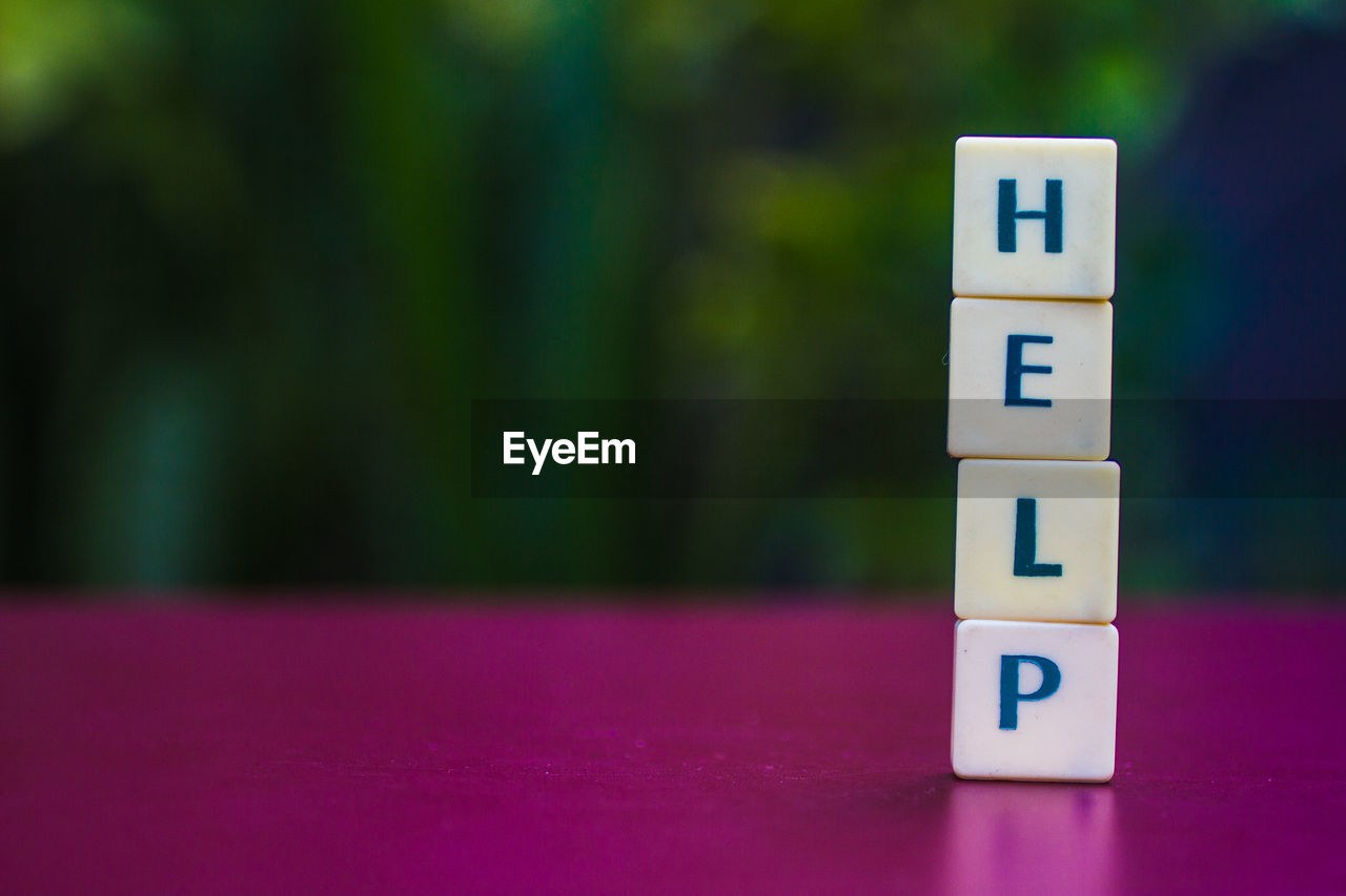 Close-up of toy blocks stack forming help text on table