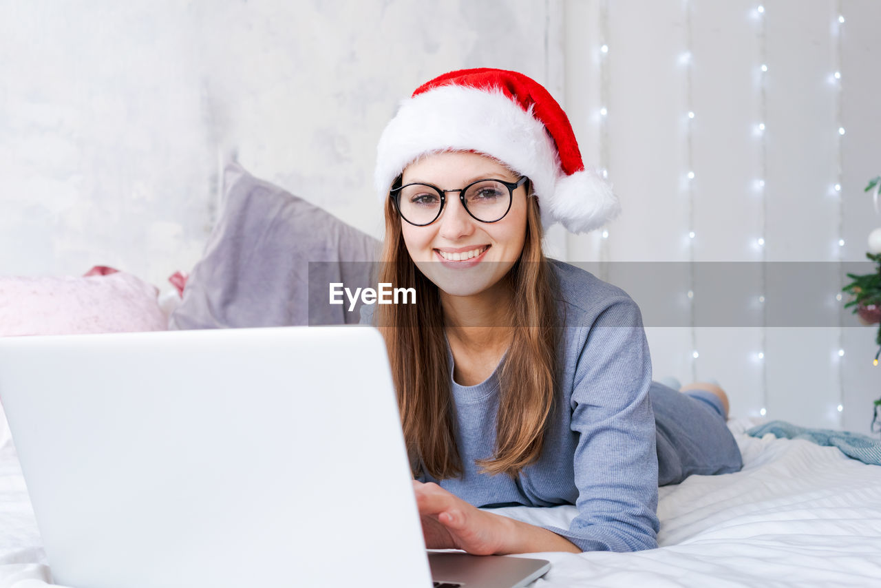 Woman in santa hat playing on laptop at christmas online shopping for holidays