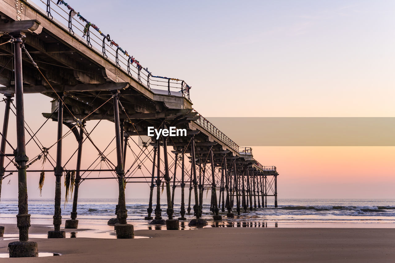 Pier over sea against sky during sunset