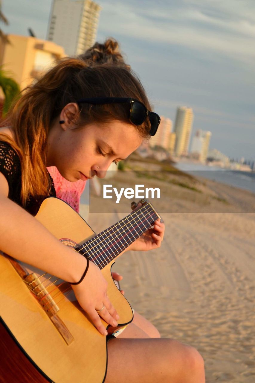 Portrait of woman playing guitar on beach