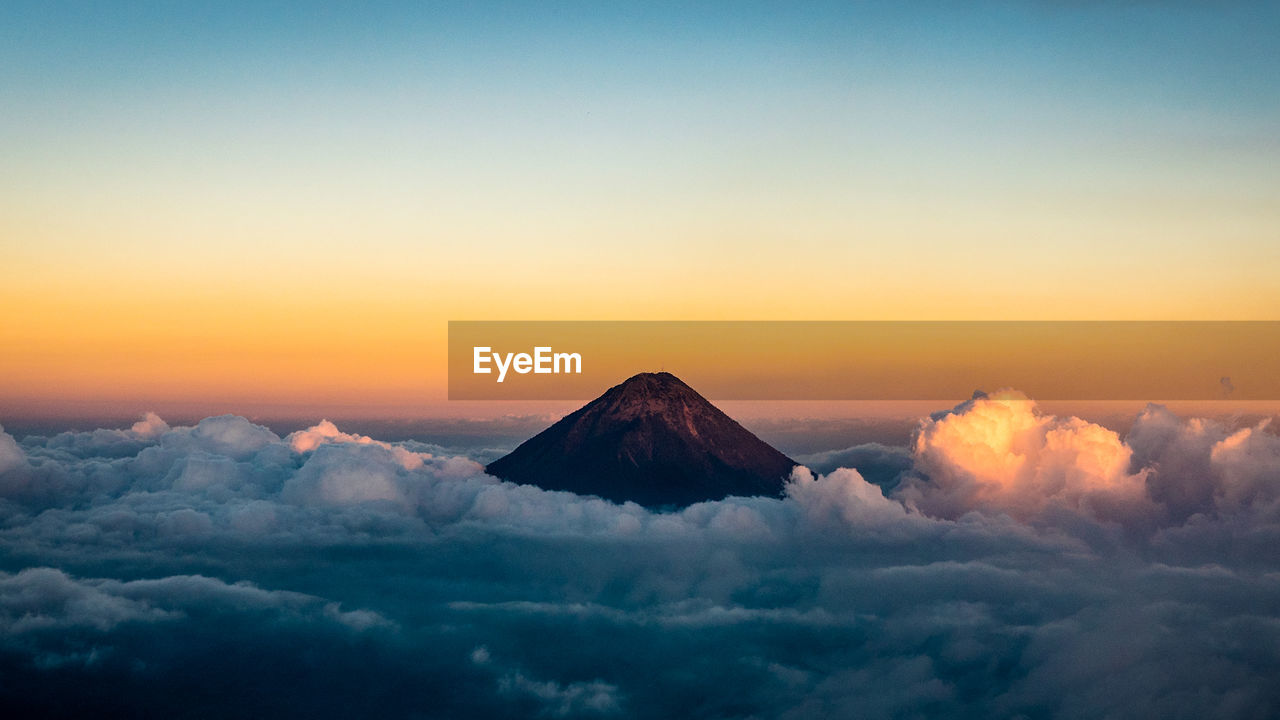 Scenic view of mountain amidst clouds during sunset