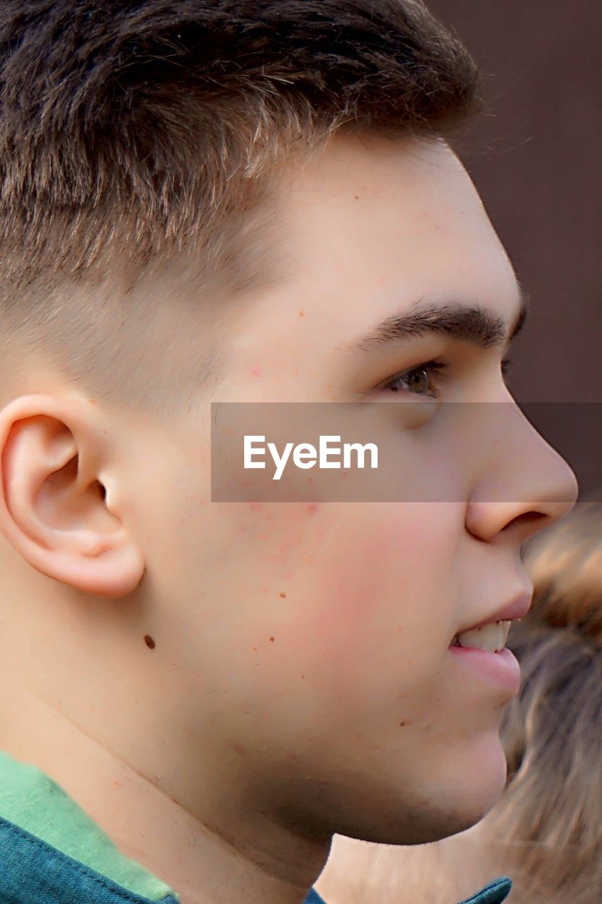 Profile view of young man standing outdoors