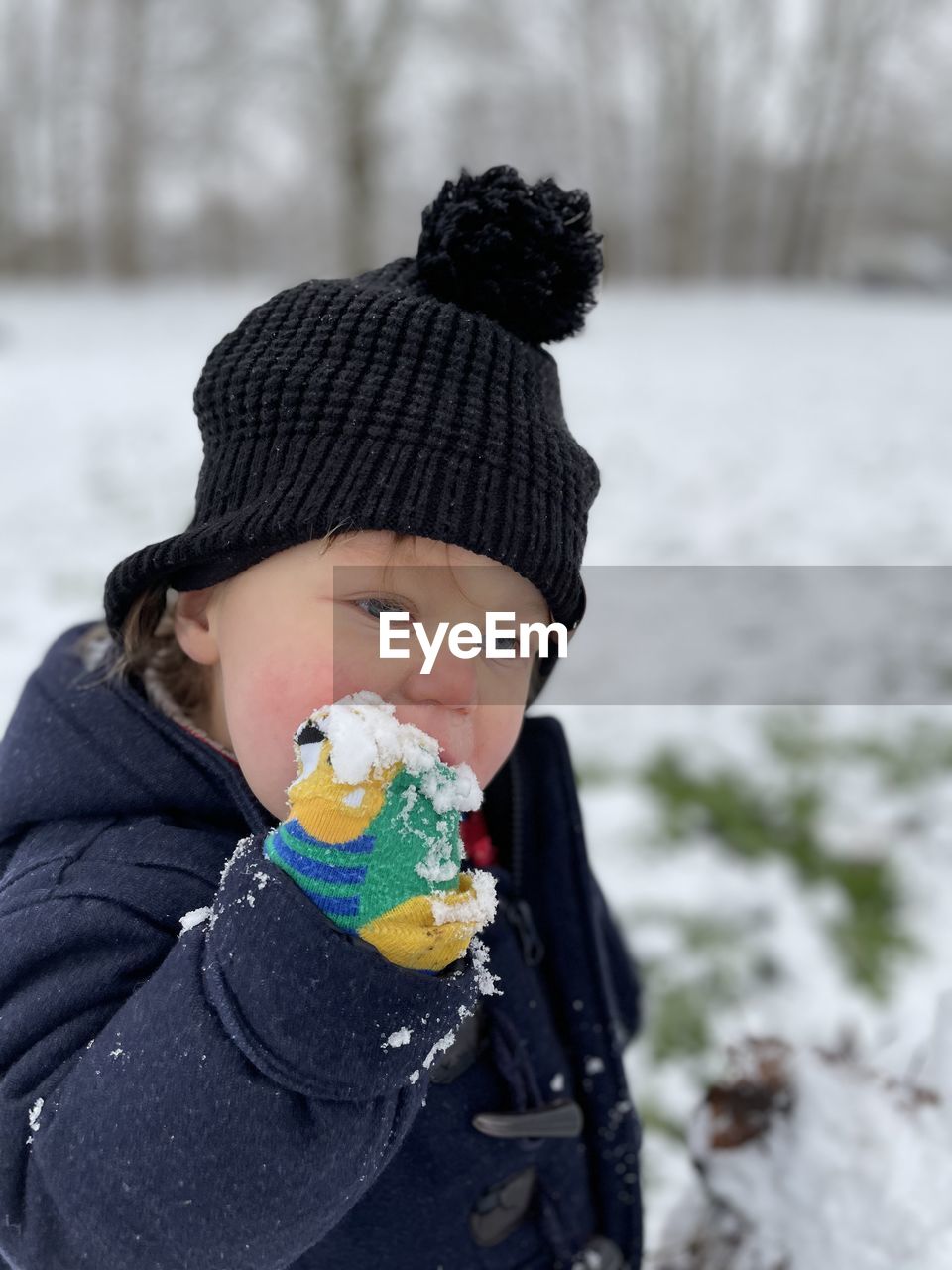 Cute boy eating food outdoors during winter