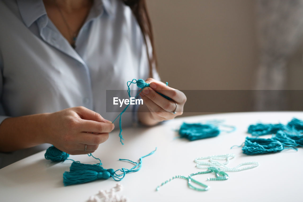 Woman working with threads and beads close-up, concept creativity,  hobby and small business.