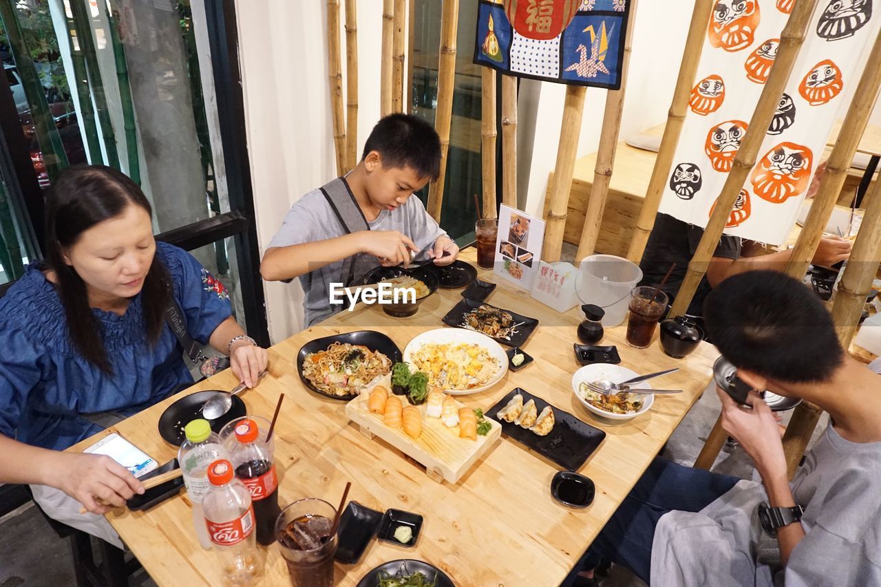 HIGH ANGLE VIEW OF PEOPLE SITTING AT RESTAURANT