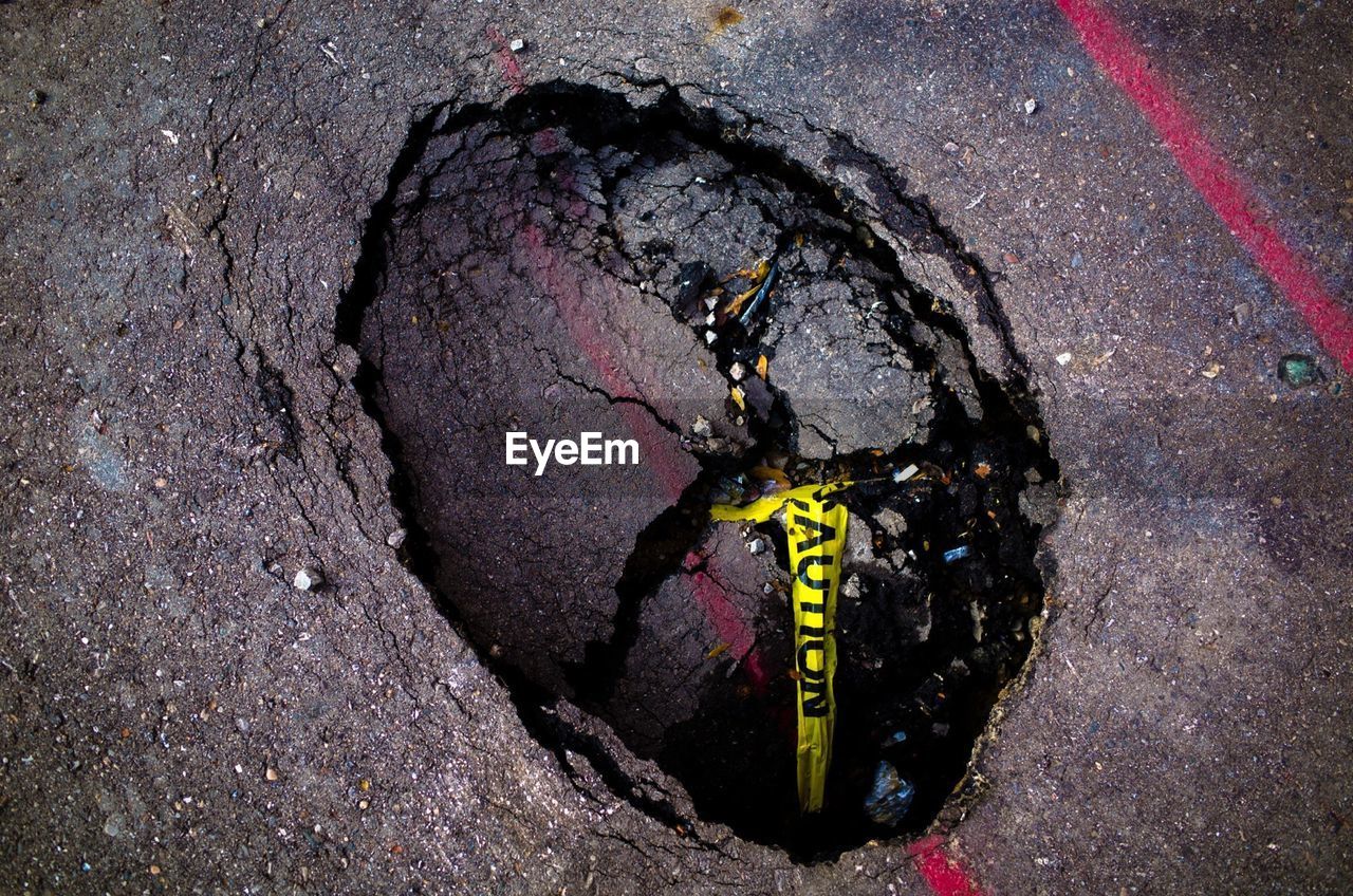 High angle view of cordon tape in hole on street