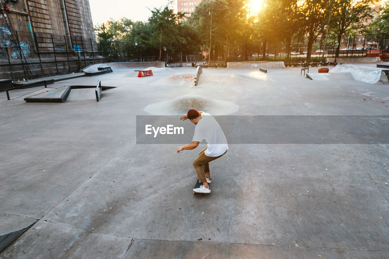 Full length of man skateboarding at skating park against building