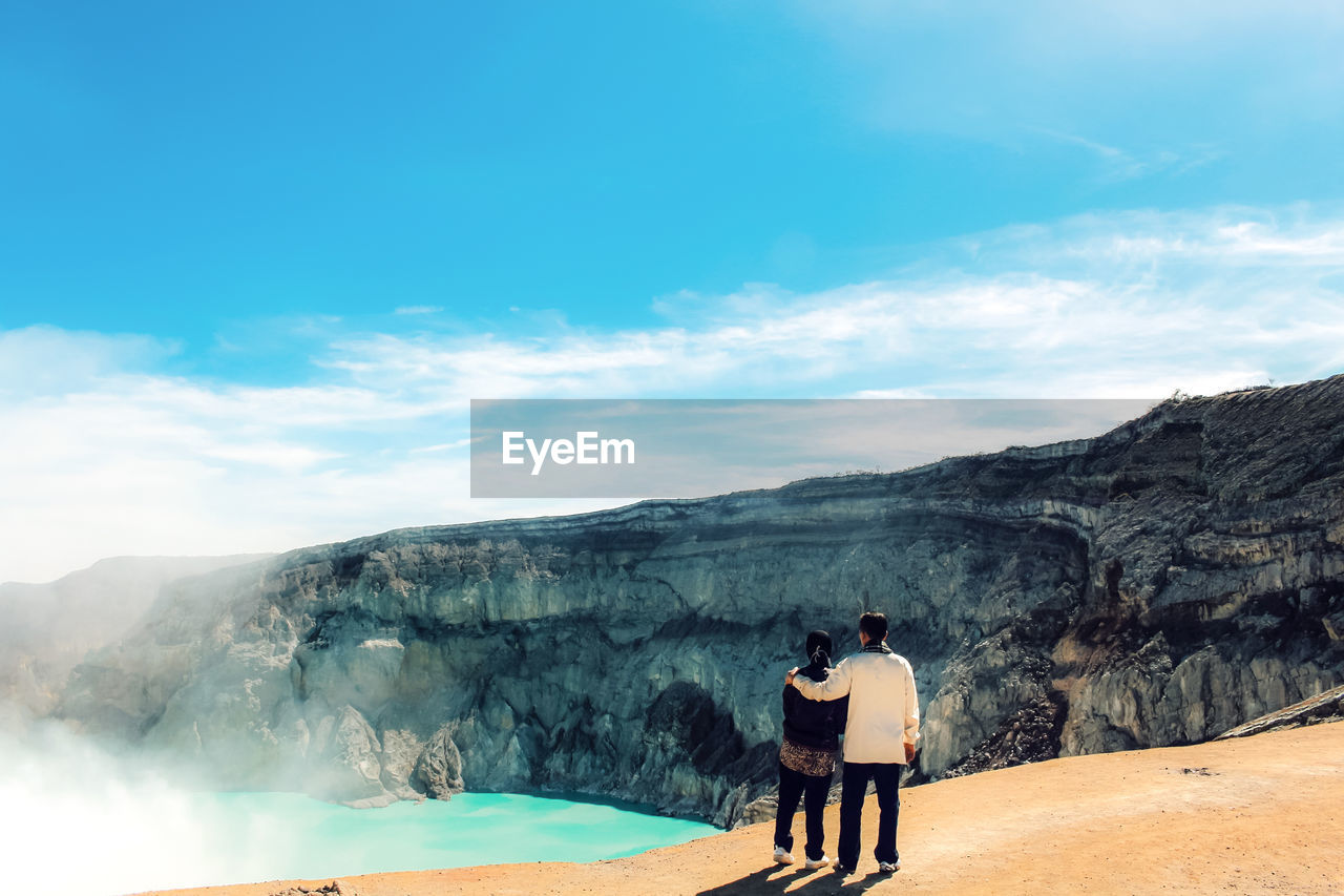 Rear view of friends standing on mountain against sky