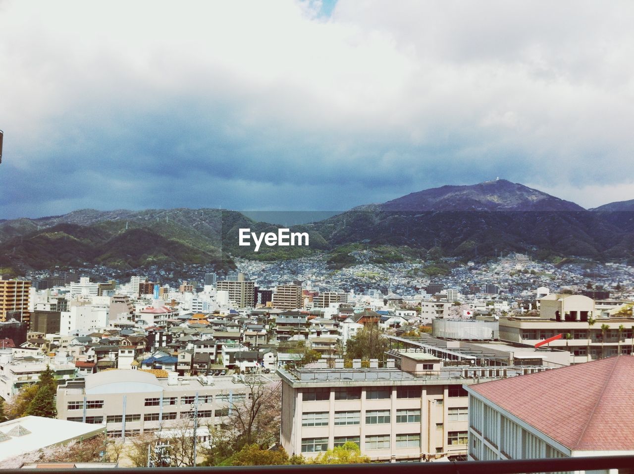 View of cityscape and mountains against cloudy sky