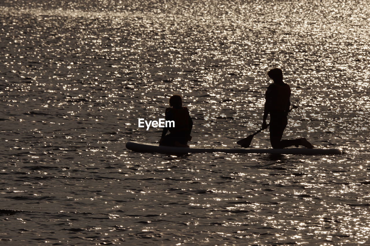 SILHOUETTE PEOPLE ON SEA AGAINST SKY