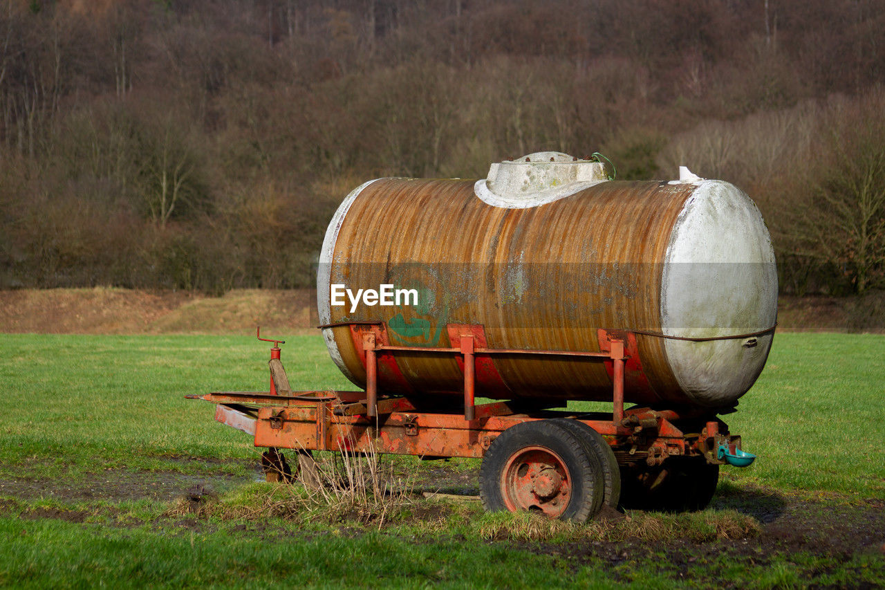 agriculture, rural area, plant, farm, field, transportation, vehicle, grass, nature, land, mode of transportation, food and drink, landscape, rural scene, no people, day, land vehicle, barrel, cylinder, outdoors, environment, food, tree, agricultural machinery, hay, container
