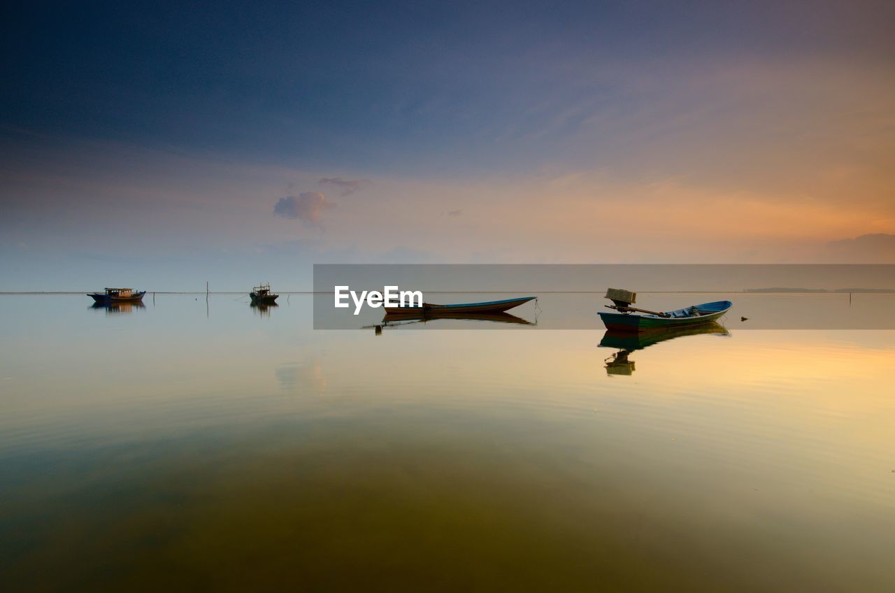 Silhouette boats moored in lake against sky during sunset