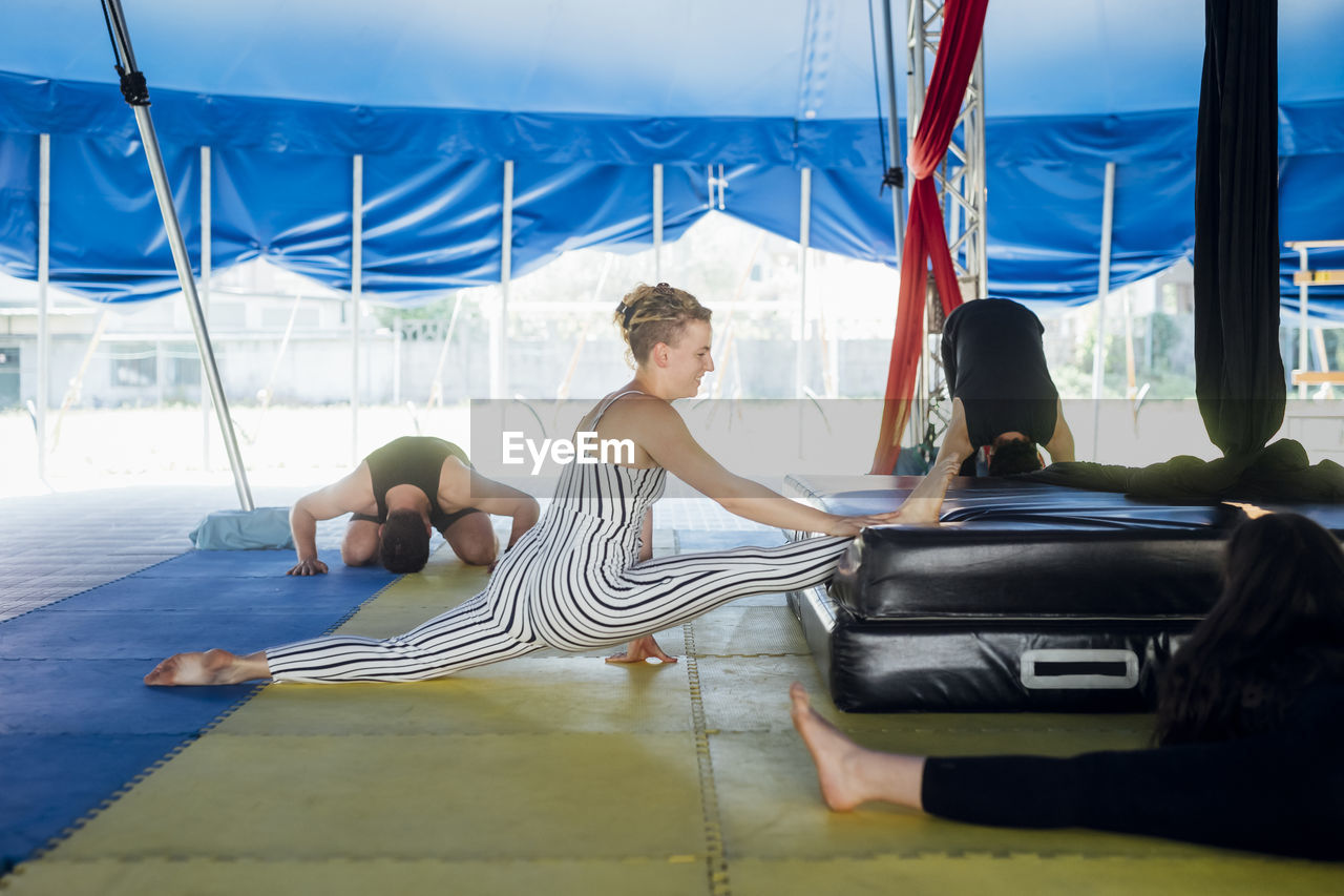 Male and female artist stretching legs during rehearsal at circus