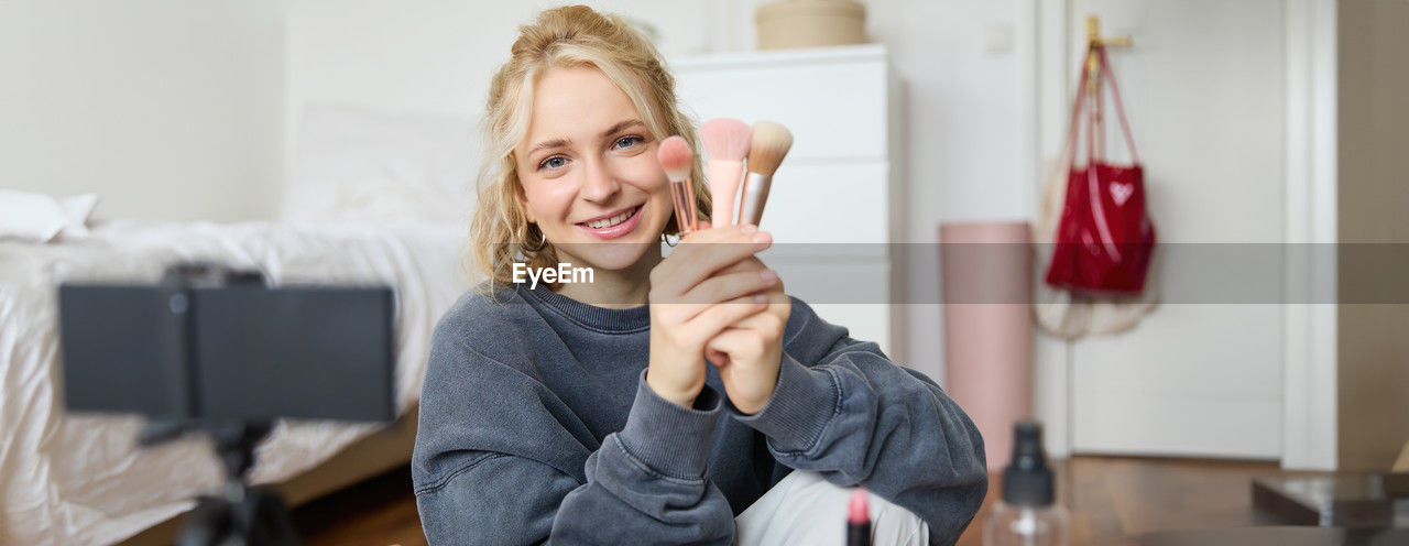 portrait of smiling young woman applying make-up to daughter