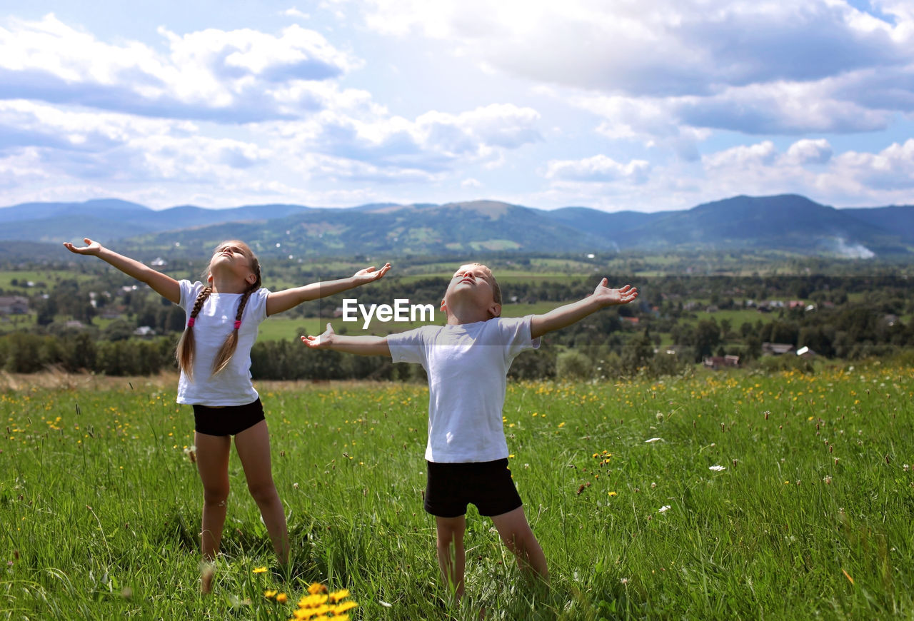 Woman with arms raised on field against sky