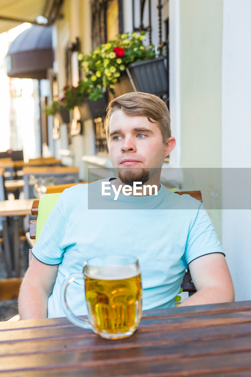 PORTRAIT OF MAN SITTING ON TABLE