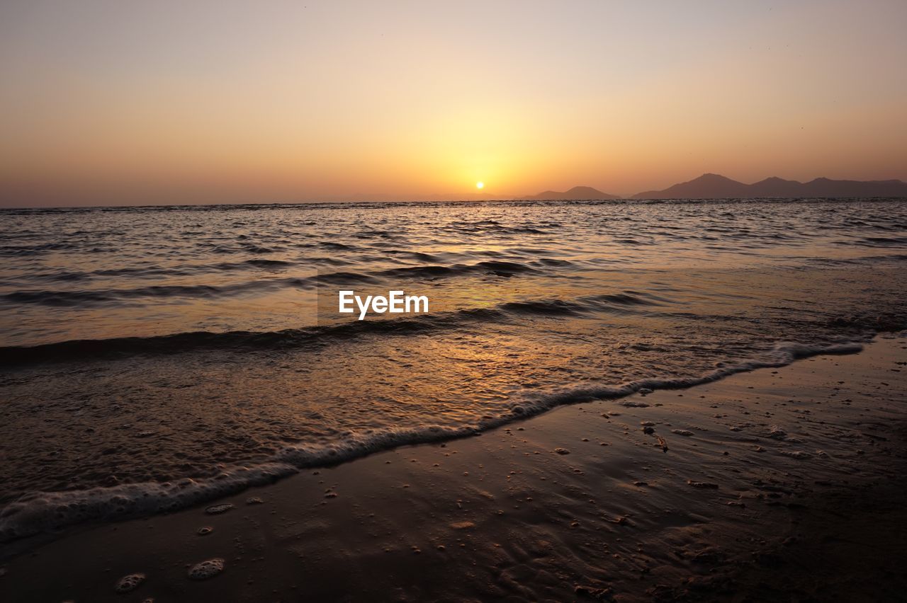 Scenic view of beach against clear sky during sunset