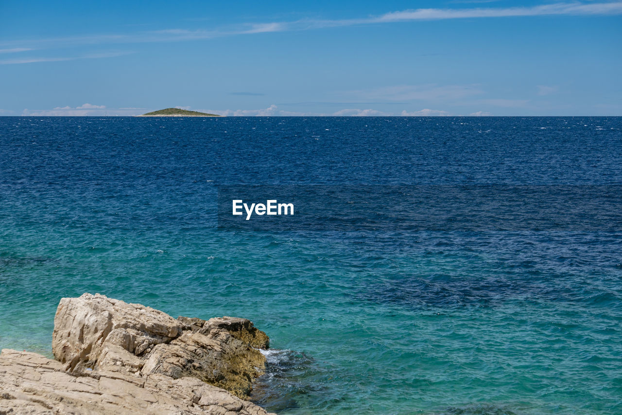 Rock formation in sea against blue sky