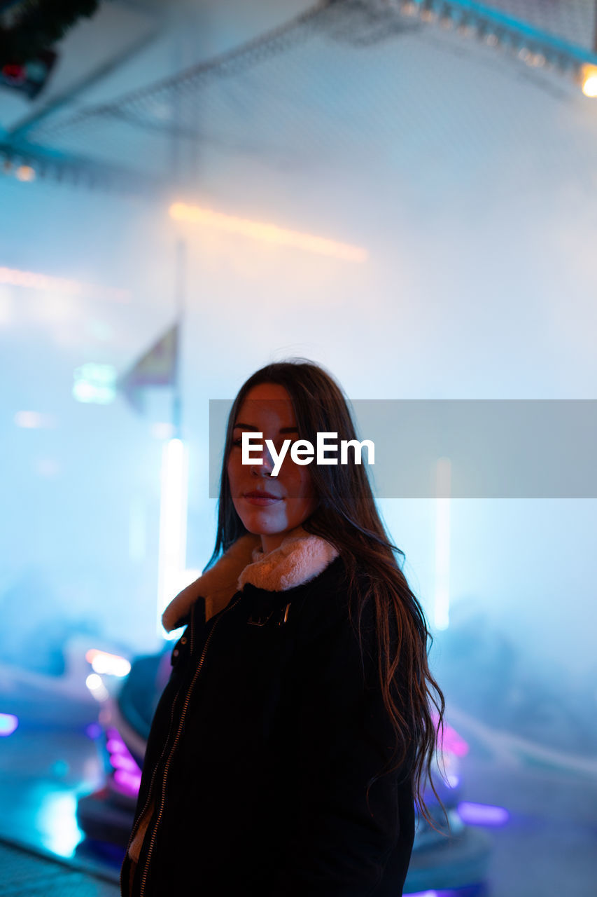 Portrait of young woman looking at illuminated camera