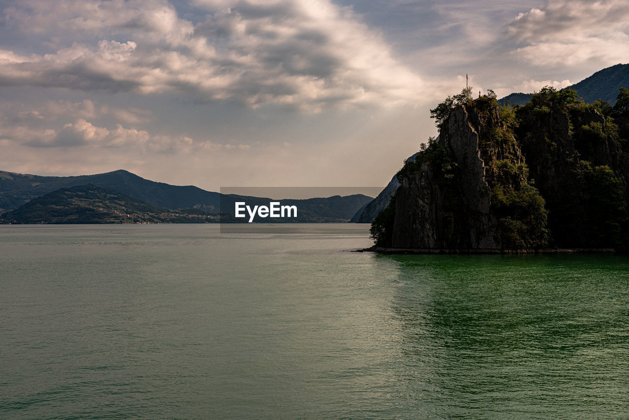 Scenic view of sea by mountains against sky