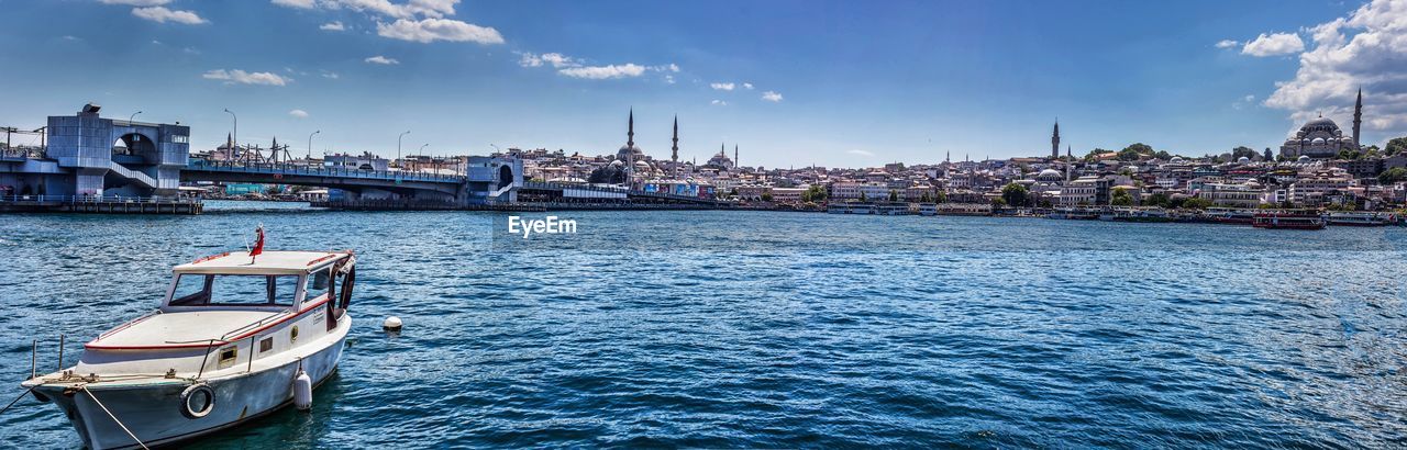 Sailboats moored on river against sky in city