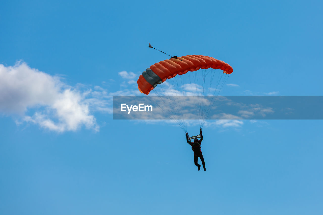 low angle view of man paragliding against clear blue sky