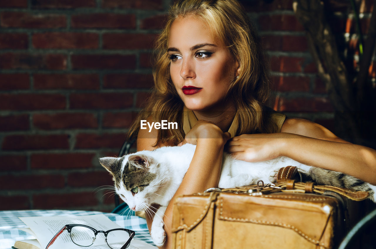 Young woman with cat sitting outdoors