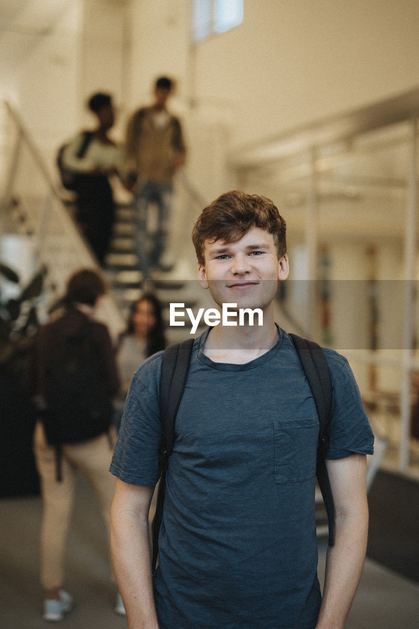 Portrait of smiling young male student standing in university