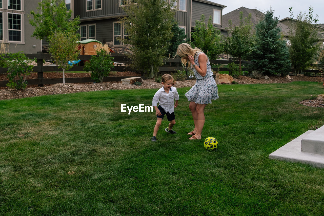 Little boy playing soccer with his mom in the yard