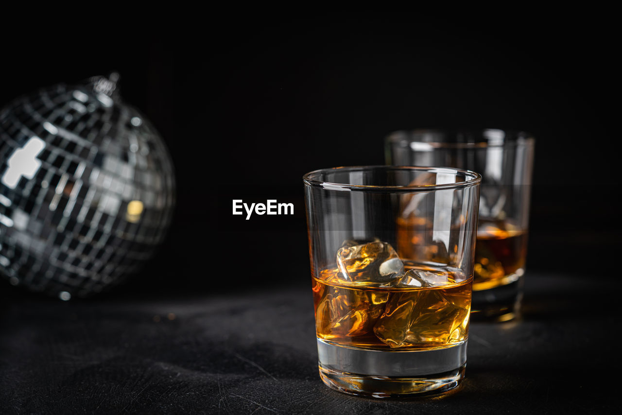 glass, drinking glass, whisky, distilled beverage, old fashioned glass, household equipment, drink, refreshment, food and drink, alcohol, black background, alcoholic beverage, indoors, studio shot, whiskey, lighting, no people, nightlife, still life, shot glass, close-up, table