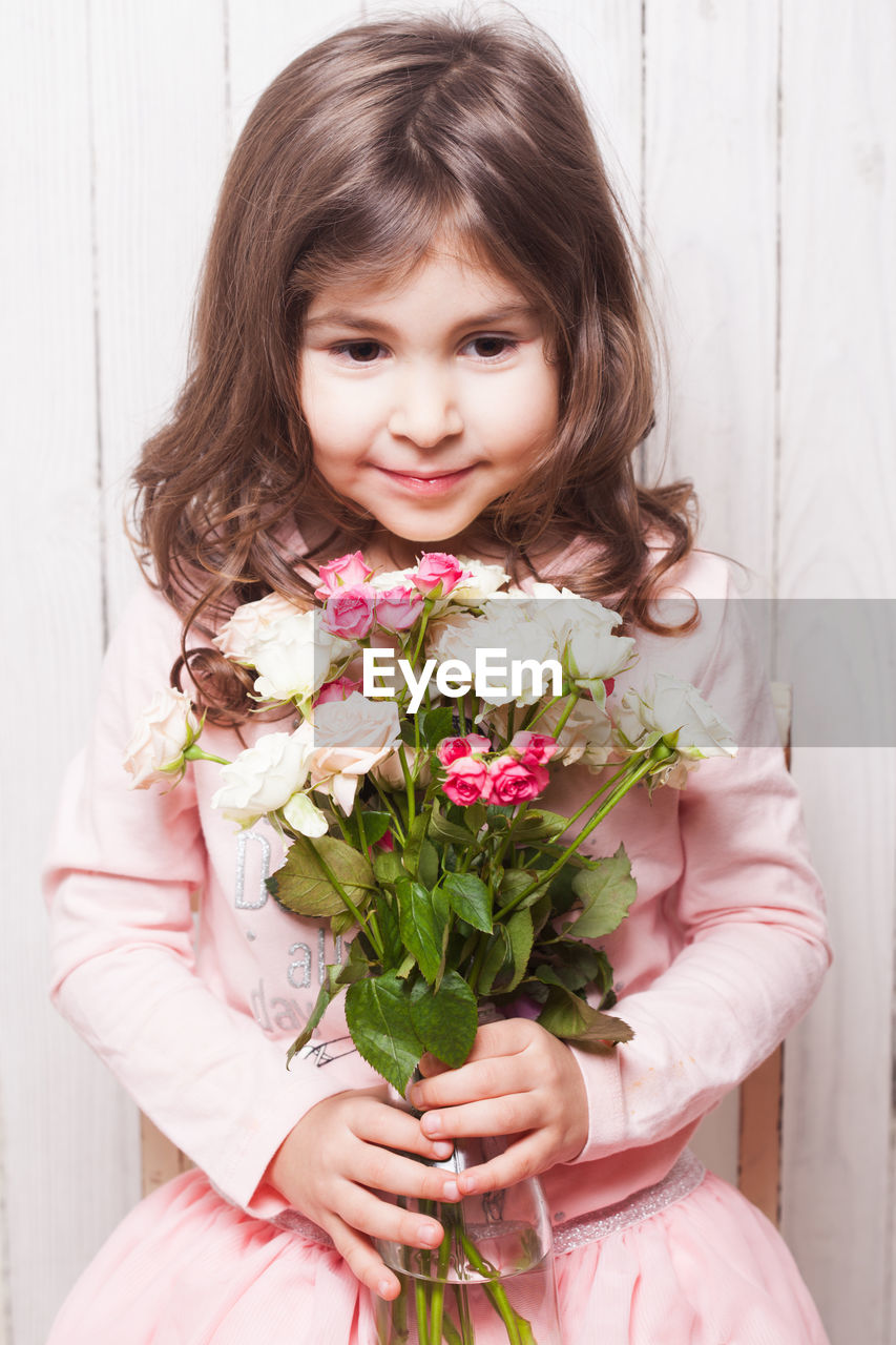 Smiling girl holding bouquet while sitting at home