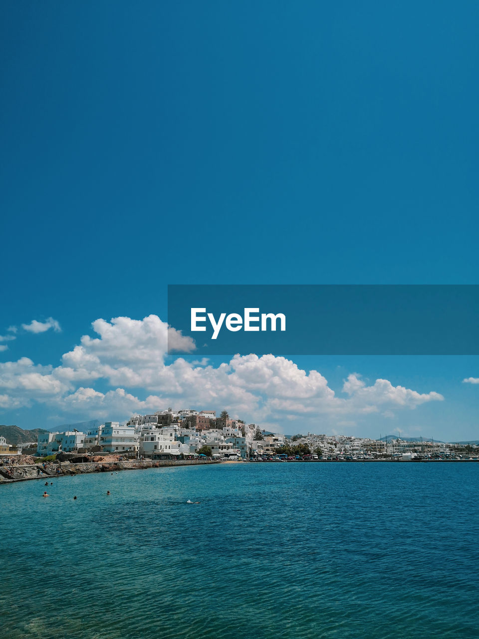 Scenic view of sea by buildings against blue sky